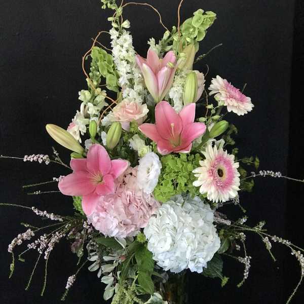 Tall pink and white floral arrangement in a glass vase