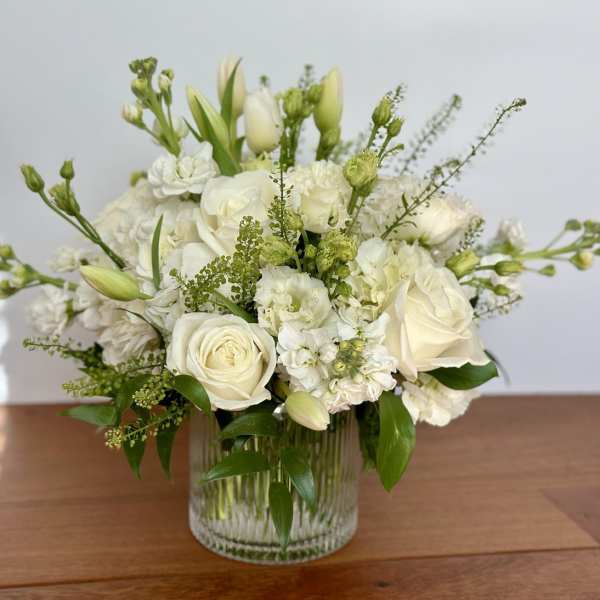 White roses and mixed white flowers in a clear glass vase