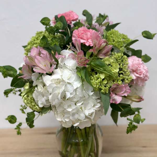 Pink and white flowers arranged in a glass vase