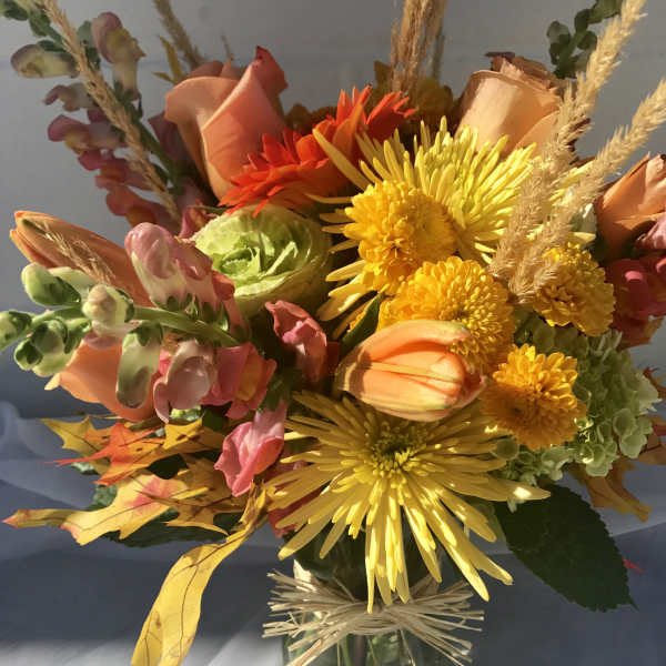 Bouquet of yellow, orange, and pink flowers in a glass vase