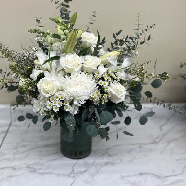 White roses and lilies arranged in a dark glass vase