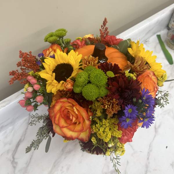 Colorful bouquet with sunflowers, roses, and chrysanthemums around a pumpkin