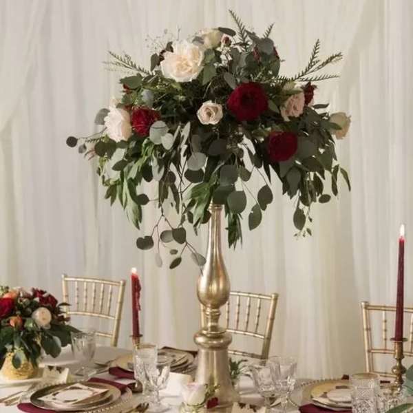 Tall floral centerpiece with red and white roses on a gold stand
