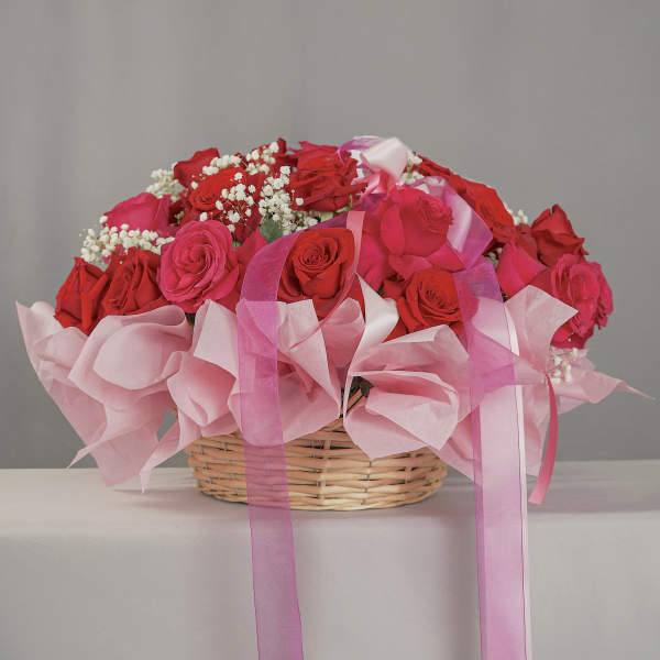 Basket of red and pink roses with baby’s breath and pink ribbons