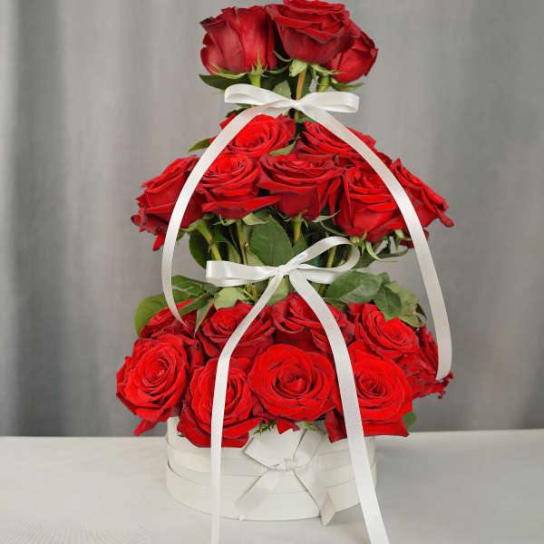 Tiered arrangement of red roses in a white box with ribbon bows