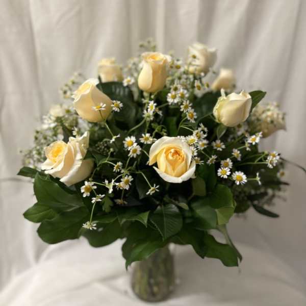 Cream roses and small white daisies in a glass vase