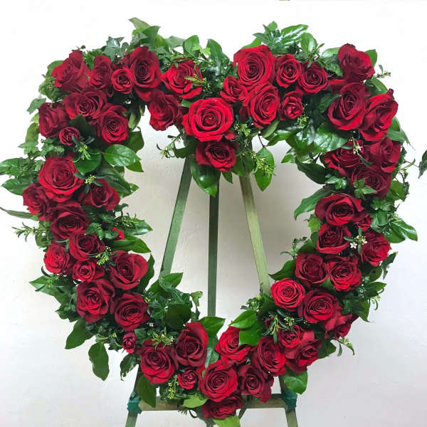 Heart-shaped wreath of red roses displayed on a standing easel