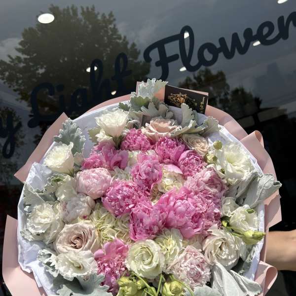 Pink and white bouquet with roses and peonies wrapped in pale paper