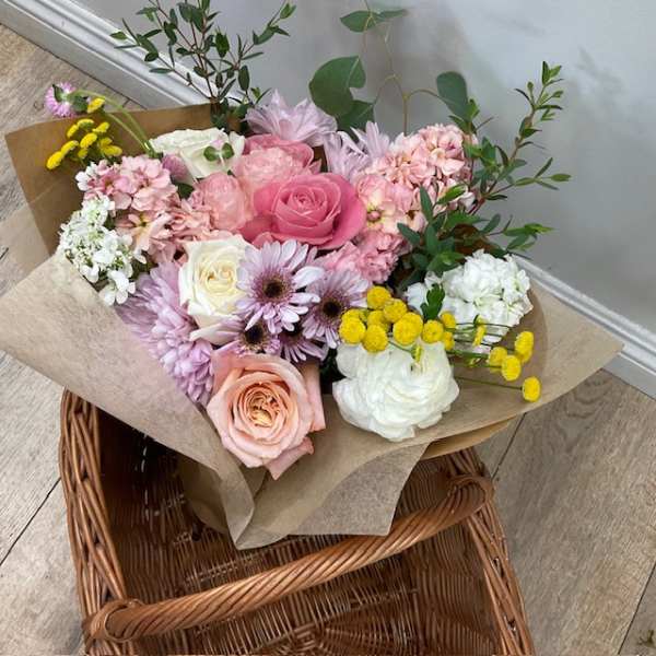 Bouquet of pink, white, and yellow flowers wrapped in brown paper