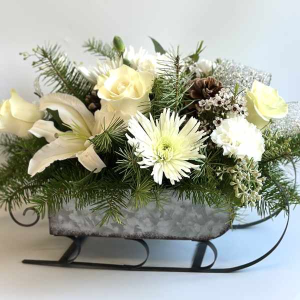 Winter floral arrangement in a sleigh-shaped container with white blooms