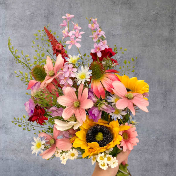 Handheld bouquet of mixed pink, yellow, and white flowers