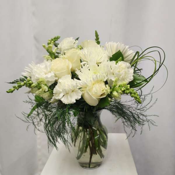 White bouquet of roses, chrysanthemums, and carnations in a glass vase