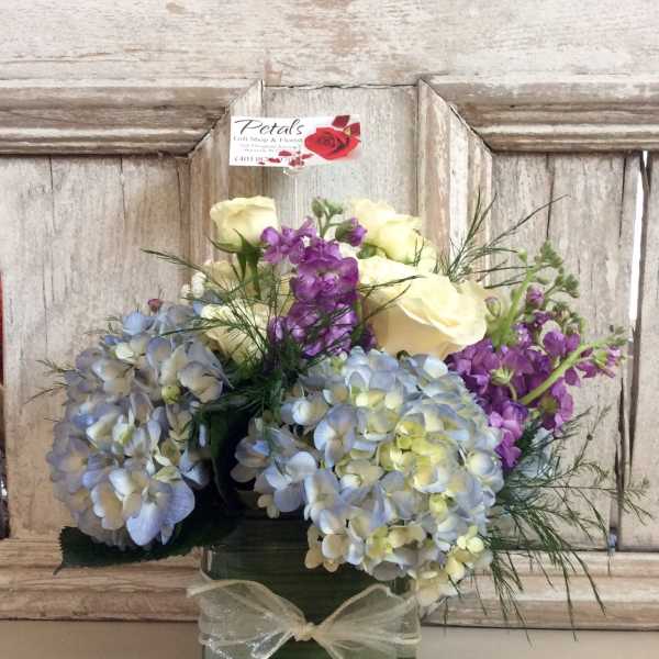 Bouquet of pastel hydrangeas, purple stock, and cream roses in a green vase