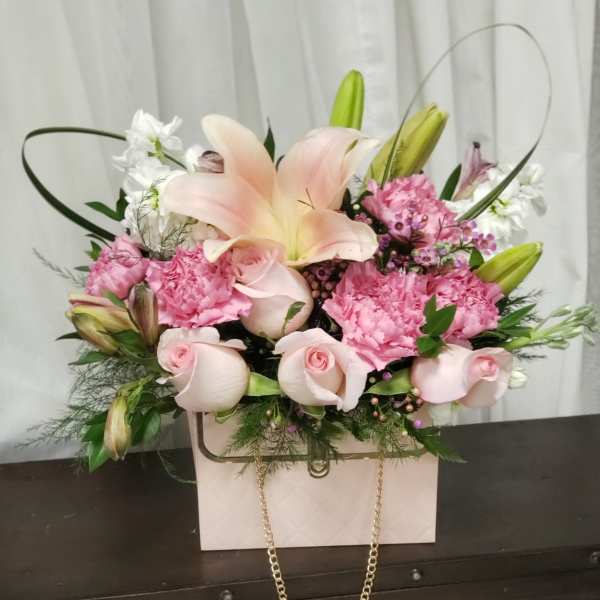 Pink and white floral arrangement in a pale gift box with a gold chain handle