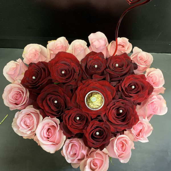 Heart-shaped rose arrangement with pink and red roses and a heart topper