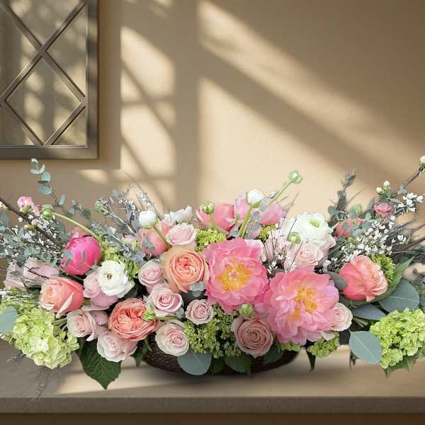 Low floral centerpiece with pink and white roses and peonies in a shallow container