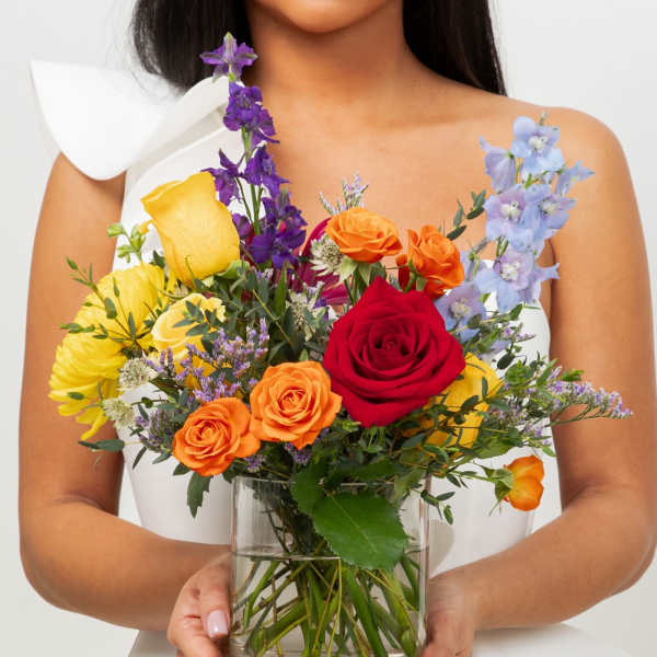 Woman holding a colorful mixed bouquet in a glass vase
