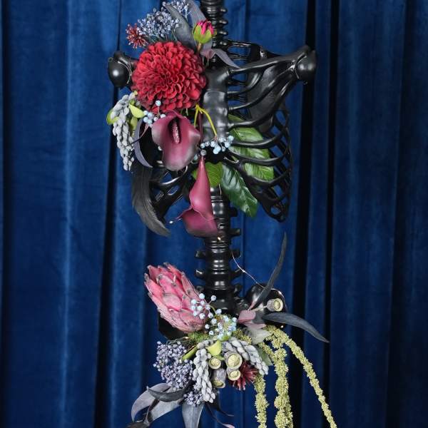 Floral arrangement on a black ribcage sculpture with cascading blooms