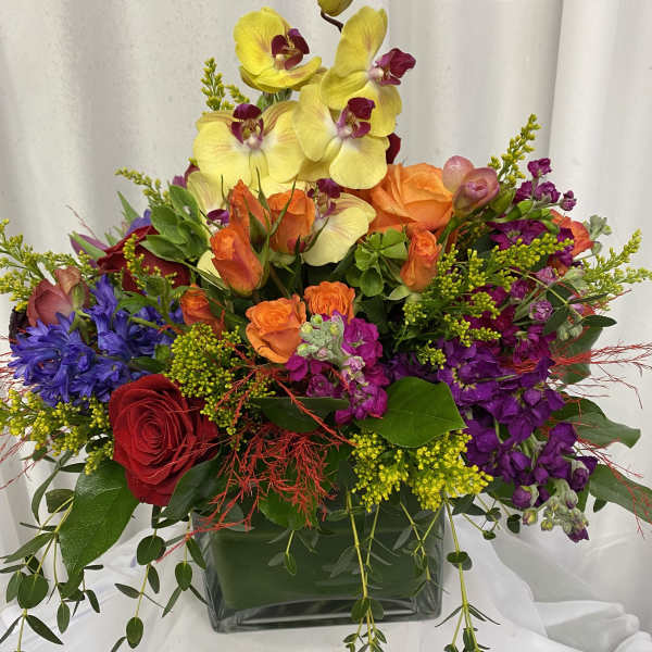 Colorful mixed flower arrangement in a square glass vase