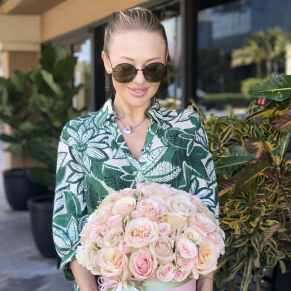 Woman holding a pink box of pale pink roses