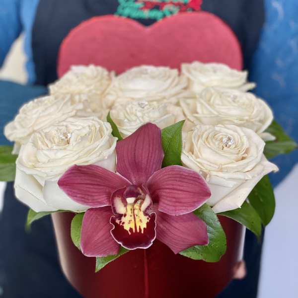 White roses in a red heart-shaped box with a pink orchid