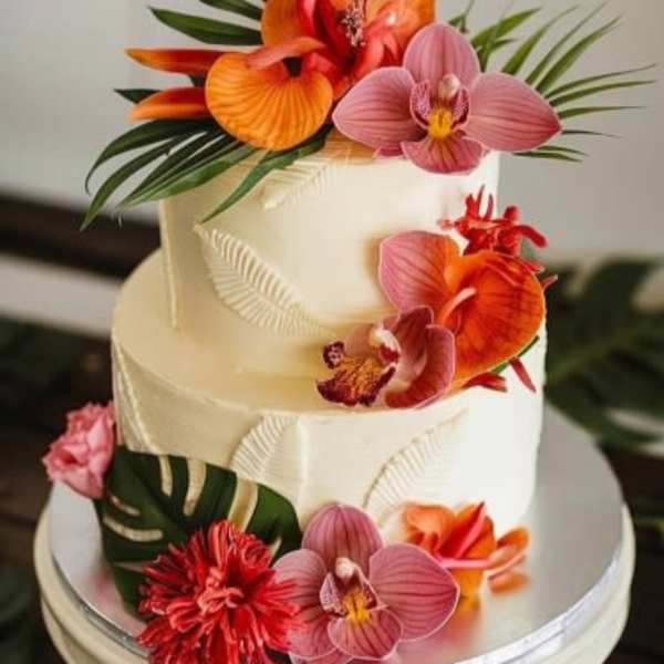 Two-tier white cake decorated with bright tropical flowers