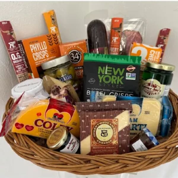 Gift basket filled with assorted snacks, cheeses, and jars in a wicker basket
