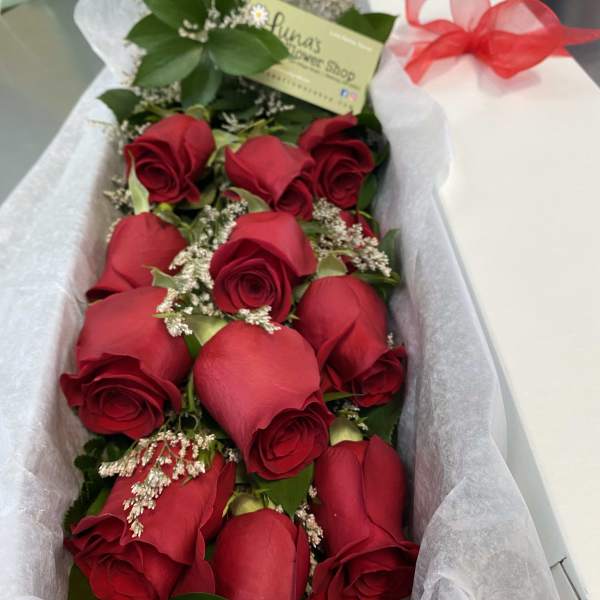 Bouquet of red roses wrapped in white paper with a red ribbon