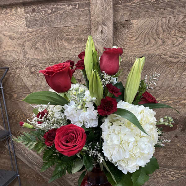 Red roses and white hydrangeas in a red glass vase