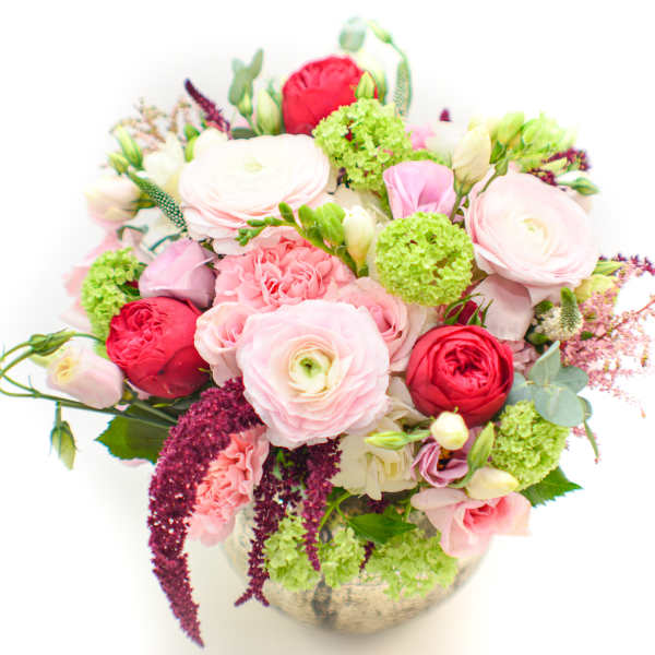 Mixed pink and red flowers arranged in a round vase