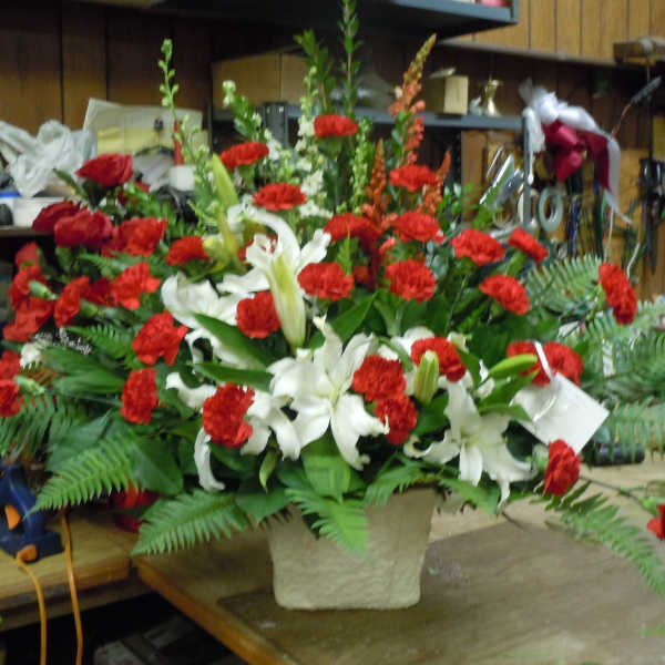 Large red and white floral arrangement in a textured vase