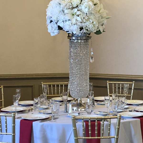 White floral centerpiece on a tall crystal-covered stand