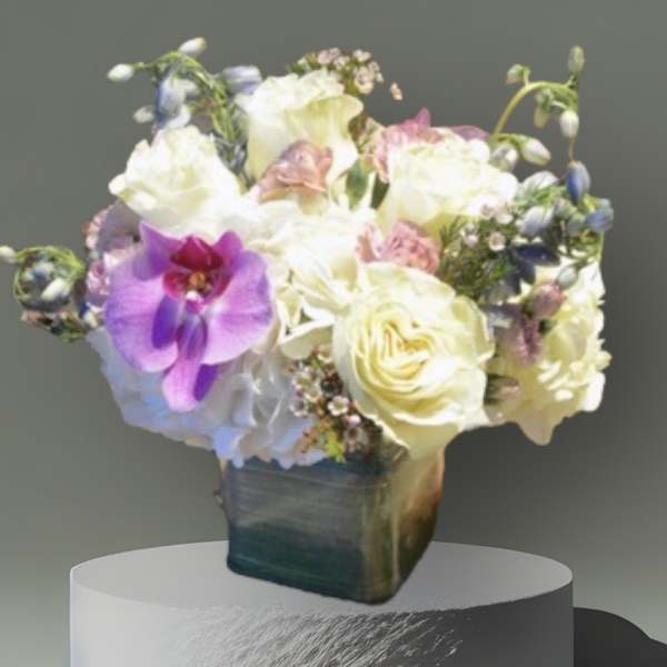 Bouquet of white and purple flowers in a square vase