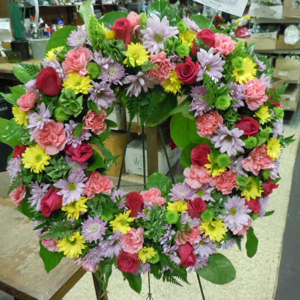 Heart-shaped floral wreath with pink, red, yellow, and lavender blooms