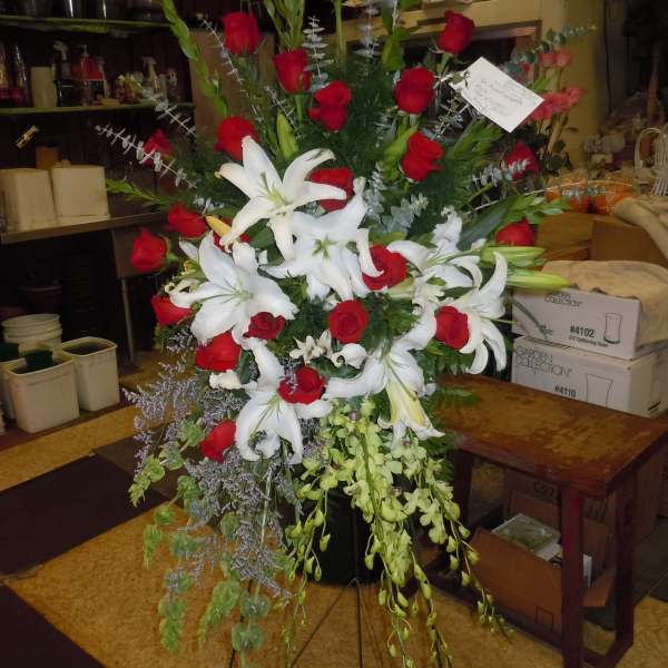 Tall floral spray with red roses and white lilies on a stand