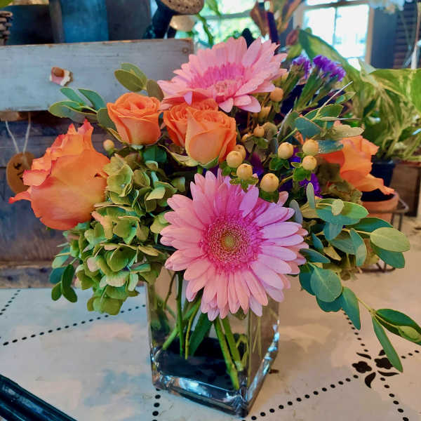 Pink gerbera daisies and orange roses in a clear glass vase