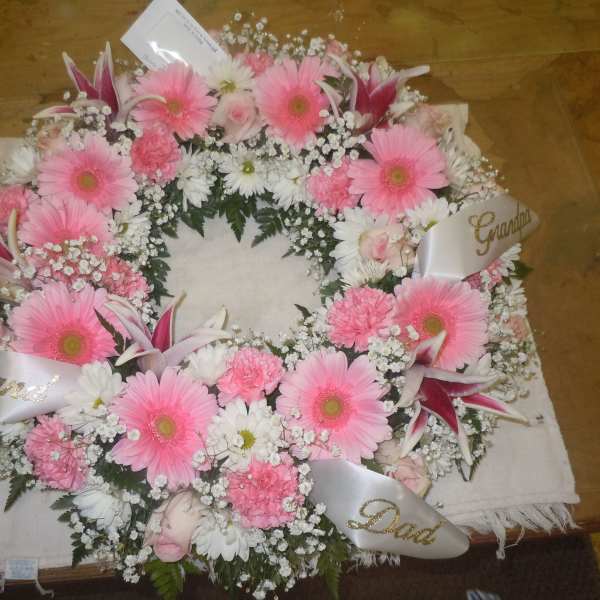 Pink and white funeral wreath with ribbon labels for family members