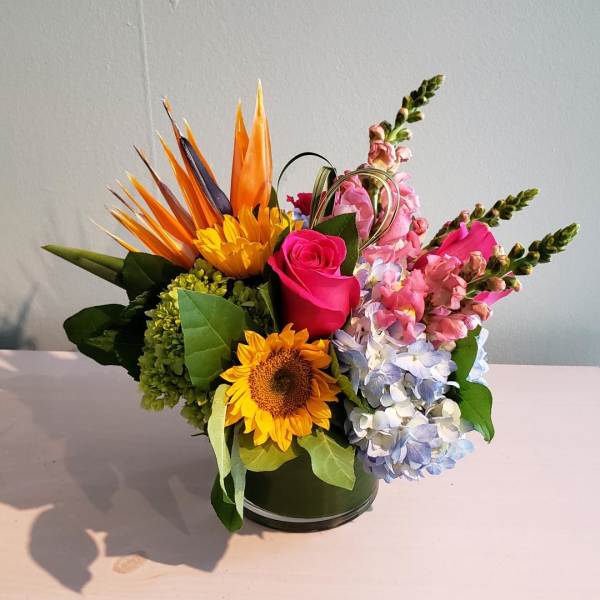 Mixed bouquet in a round vase with sunflower, roses, hydrangea, and snapdragons
