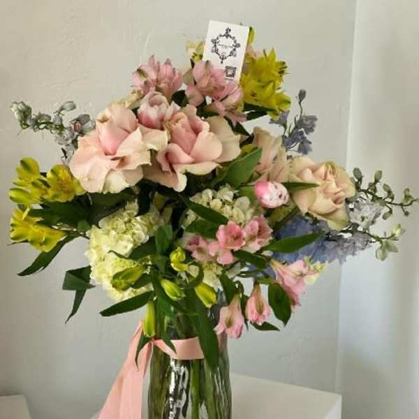 Pink and yellow mixed bouquet in a glass vase with a pink ribbon