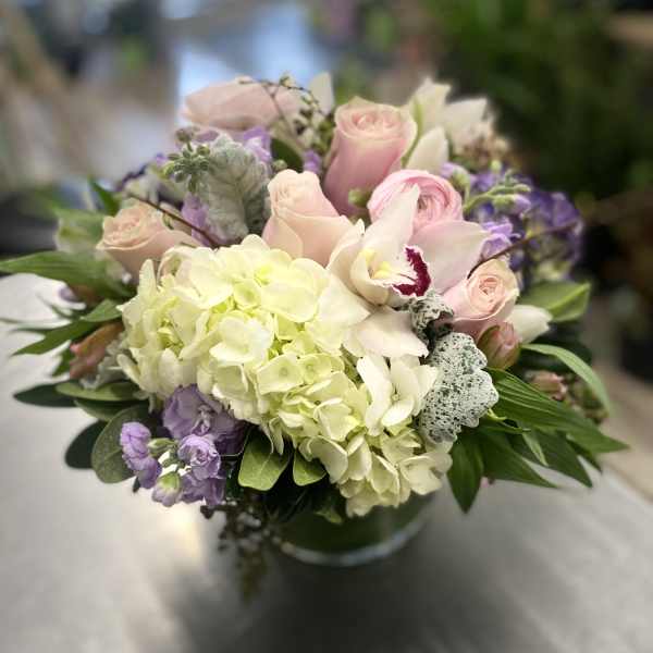 Bouquet of pale pink roses, white hydrangea, and purple flowers in a vase