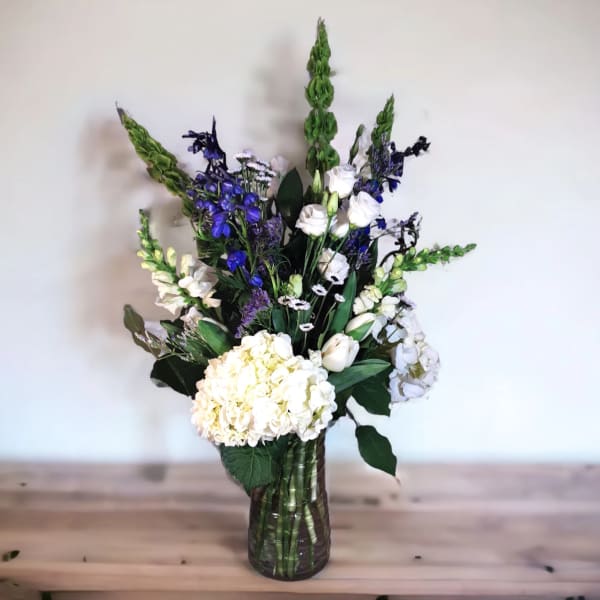 White and blue floral arrangement in a glass vase