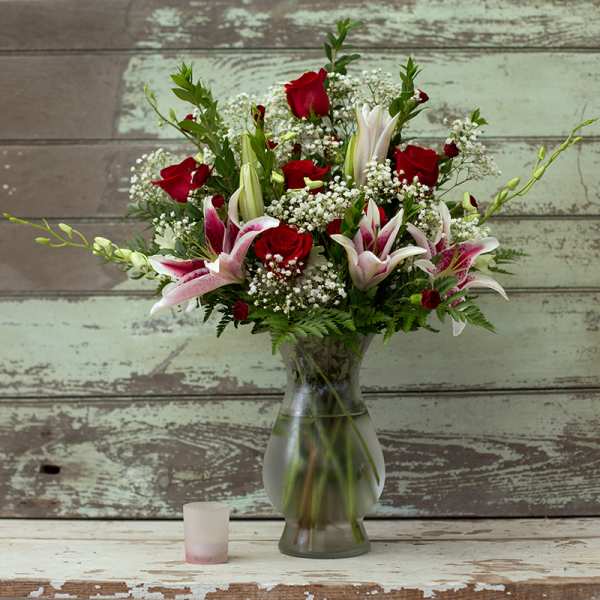 Red roses and pink lilies arranged in a glass vase