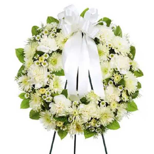 White floral funeral wreath on a standing easel with a ribbon bow