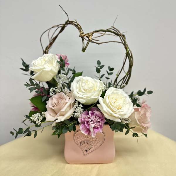 Romantic arrangement of white and blush roses with pink carnation in a pink heart vase with twig heart