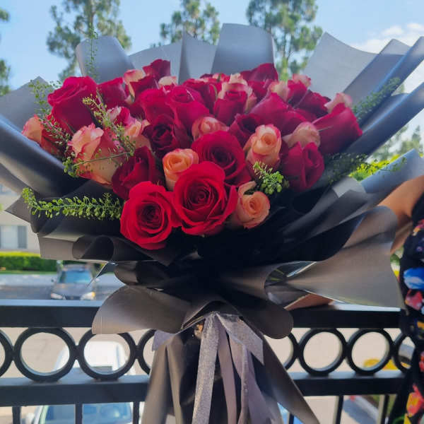 Bouquet of red and peach roses wrapped in black paper