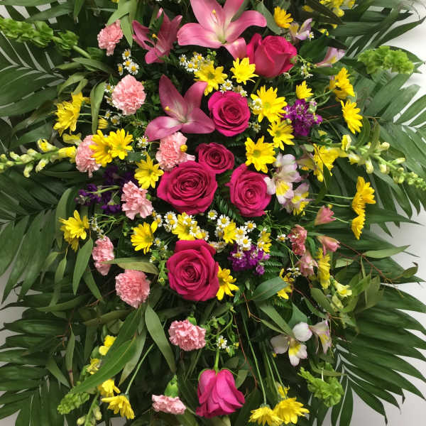 Large standing floral spray with pink roses, lilies, and yellow daisies