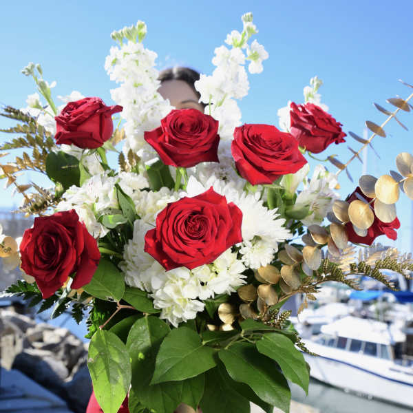 Bouquet of red roses and white flowers in a gold vase