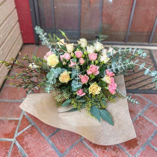 Bouquet of pink and cream roses with eucalyptus in kraft paper