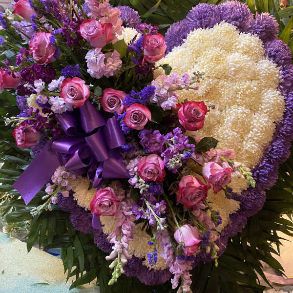Large purple and pink floral standing arrangement with a ribbon bow