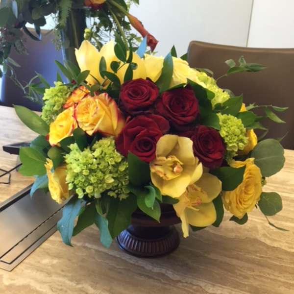 Mixed bouquet of red and yellow roses in a dark vase